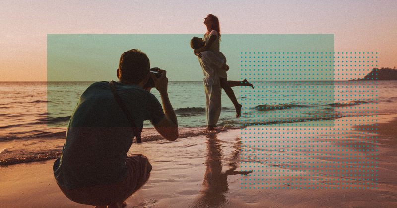 Freelancer taking a photo of a couple on the beach